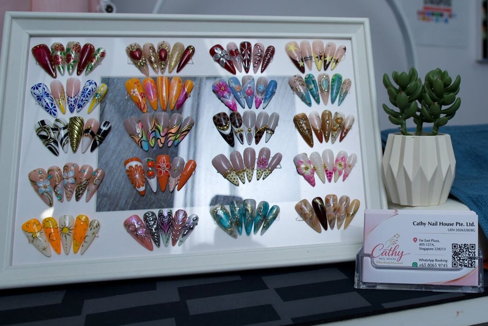 A Cathy Nail House workstation, a design sample board, the salon's business card and its embroidered towel